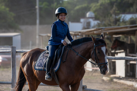 Happy young girl smiling while riding a bay horse