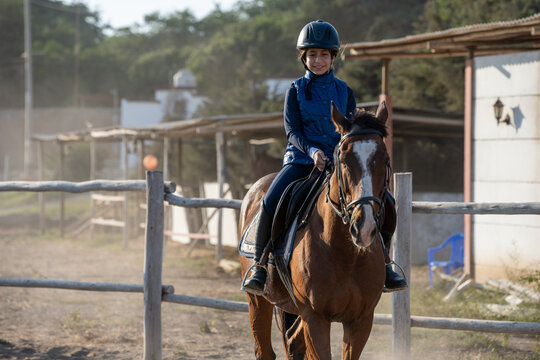 Happy young girl equestrian rides in a paddock