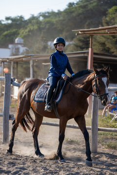 Teen girl riding bay horse during equestrian training outdoors in Peru