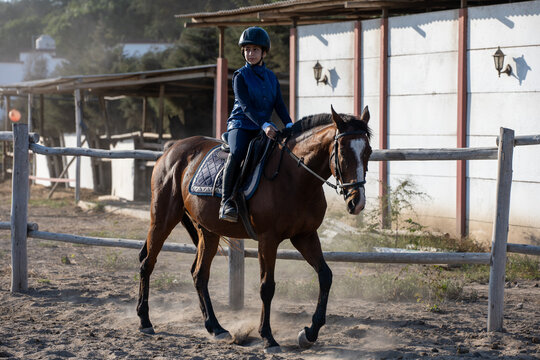 Young girl horseback riding in a sandy paddock