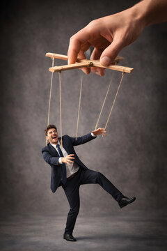 Businessman controlled by puppet strings, corporate manipulation and workplace control concept. Human marionette under external influence, leadership domination, psychological pressure, office politic