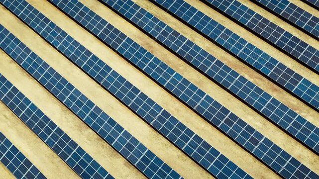 Solar panels in parallel rows on dry ground, aerial close-up of photovoltaic system for renewable electricity generation and energy transition.