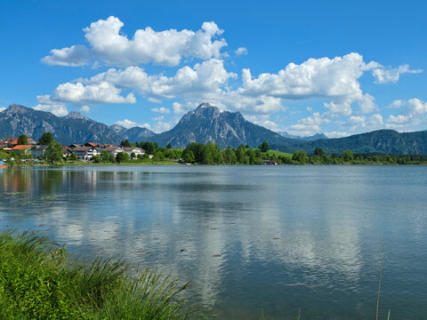 Germany, Lakeshore at Hopfen am See with village houses and snow covered alpine mountains