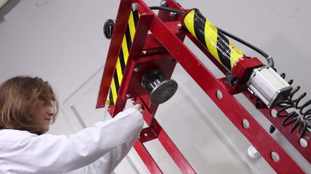 Engineer in lab coat taking measurements and inspecting industrial hydraulic press