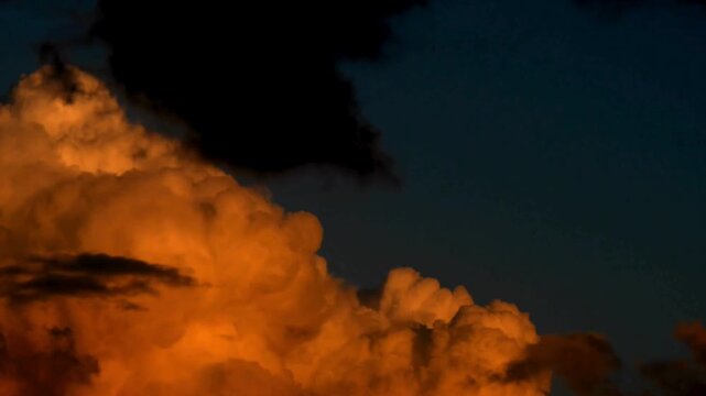 Dramatic sunset clouds with golden light, dark storm clouds moving across evening sky, cinematic orange cumulus cloudscape at twilight