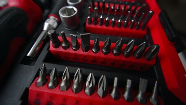 Universal tool kit with diverse screwdriver bits and metal sockets stored in red plastic organizer.