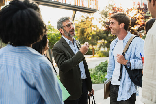 University Professor Talking With group of Students On Modern Uni Campus. Motivational Education Speech