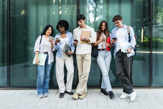 Mba business master students using smartphones standing together at University campus