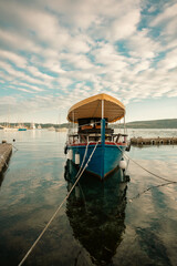 Obraz premium Vintage rowboat moored at a marina coastline during a golden hour evening sunset.