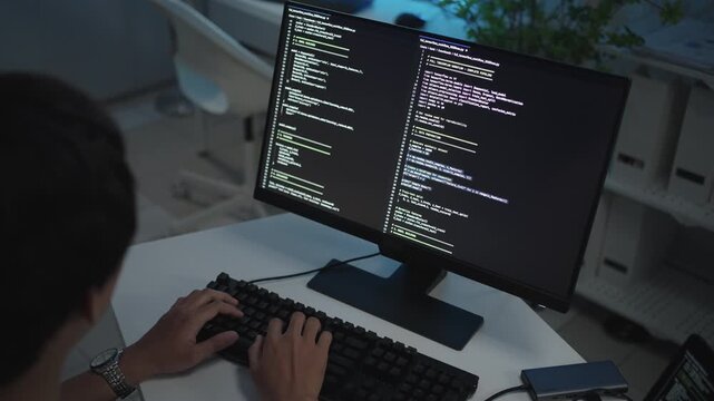 IT developer working online software development on pc monitors at modern home office on coding application screens. Man creating a software. Abstract futuristic coding concept.