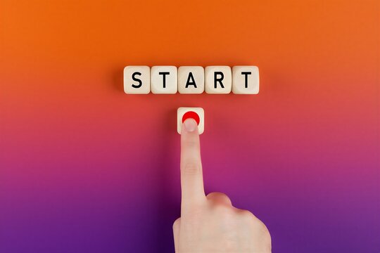 Human finger pressing a start button with wooden blocks spelling start on gradient background