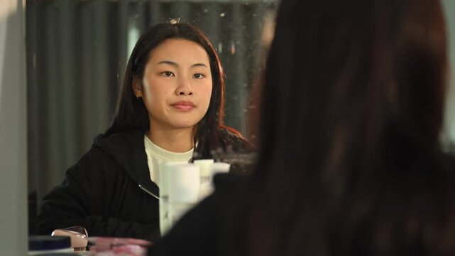 A teenager giving herself a pep talk in the mirror before doing something great.