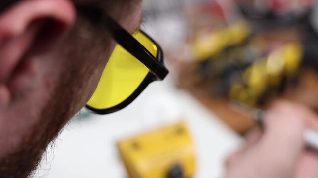 Extreme close up of a technician wearing yellow safety glasses while working in a workshop