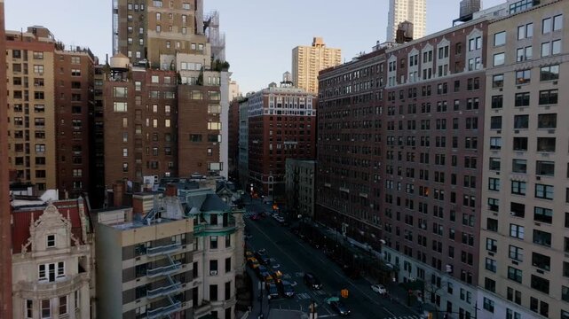 Aerial view of upper west side Manhattan city street with historic architecture and urban traffic flow at sunset.