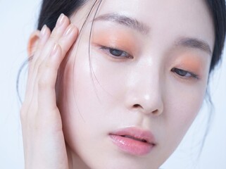 Naklejka premium Close-up portrait of a young woman with peachy eyeshadow and glossy lips
