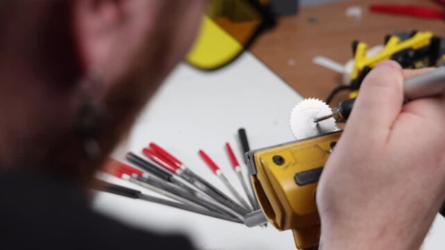 Close up of a worker with a rotary tool preparing for metal gear wheel maintenance in a workshop