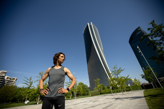 Dynamic athlete posing confidently in a bustling urban park under blue skies