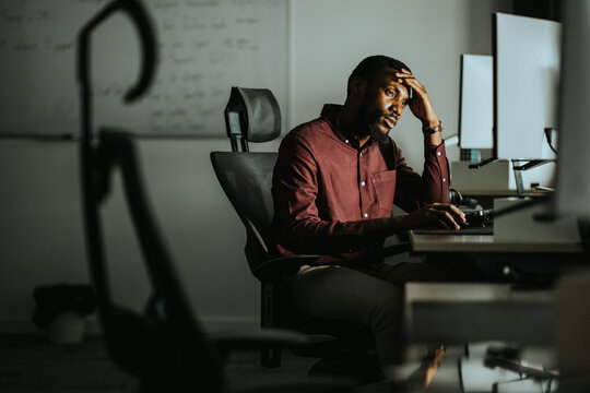 Overwhelmed worker facing challenges in a dimly lit office setting