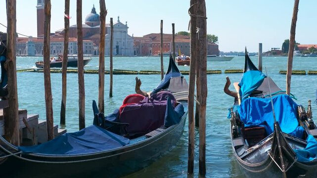 Gondolas moored in venice near san giorgio maggiore. Gondolas rest on the water surface, moored to wooden poles, creating a serene venetian scene with san giorgio maggiore church in the background