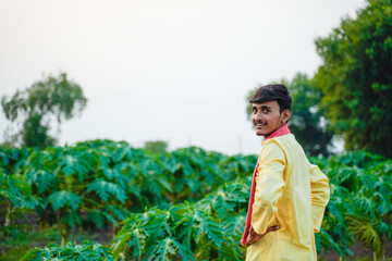 Naklejka premium Young Indian farmer standing confidently in a green papaya field