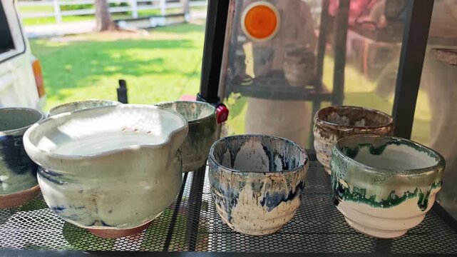 Handmade ceramic cups and pottery on a display shelf.