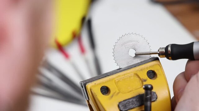 Close up of a precision rotary tool cutting bit near a circular saw blade in a vise