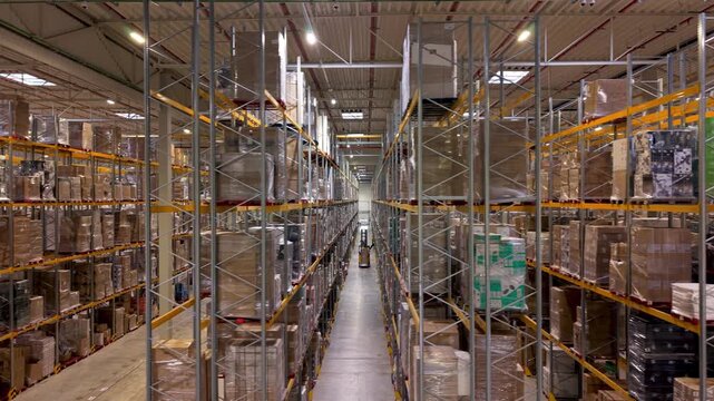 Warehouse interior showing large storage racks filled with boxes and goods. Smooth camera pan moving from right to left, illustrating industrial logistics, inventory, and supply chain management