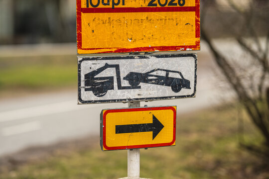 Close up of roadside towing sign with arrow direction and worn reflective surface.