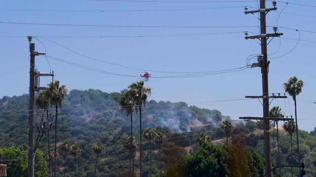 Slow motion shot of Los Angeles Fire Department responding to wildfire with aerial unit dropping water 