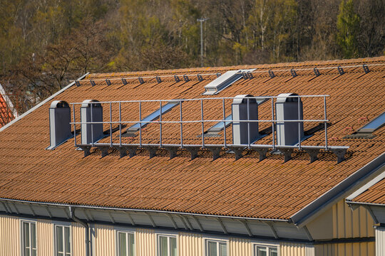 Residential tiled roof with skylights chimneys and safety railing.
