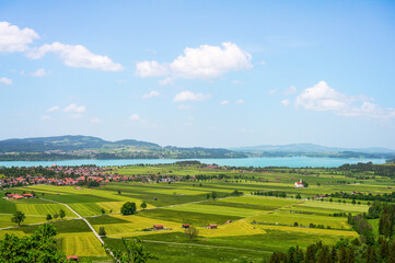Obraz premium Scenic Bavarian landscape with a village nestled beside a tranquil lake and rolling green fields