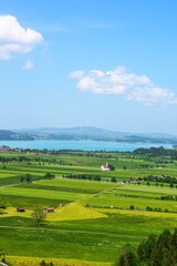 Obraz premium Scenic Bavarian landscape with a white church and turquoise lake under a blue sky