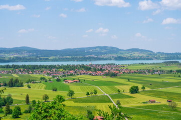 Obraz premium Scenic Bavarian village nestled beside a tranquil lake with rolling green hills