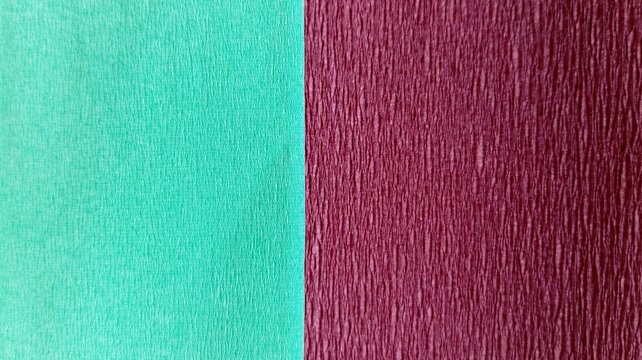 Vertical half and half corrugated paper texture backdrop in turquoise and burgundy maroon colors. Two-tone crepe paper background in rinsing water turquoise and oxblood red colors with vertical split.