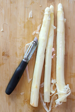 Peeling white asparagus to remove the outer layer of cellulose, preparing it for cooking.