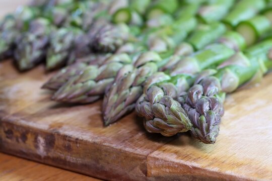 Chopped green asparagus heads on a kitchen board, preparing an asparagus dish.
