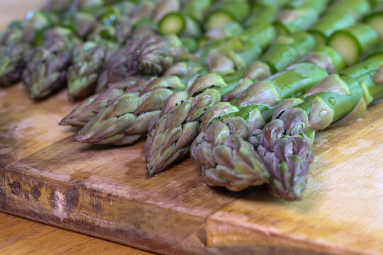 Chopped green asparagus heads on a kitchen board, preparing an asparagus dish.