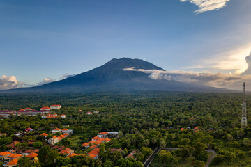 Obraz premium Mount Agung volcano towering over a lush tropical forest and village in Bali