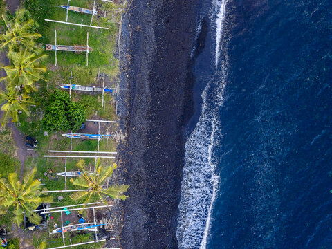 Looking down at traditional outrigger boats on black sand beach in Tulamben, Bali
