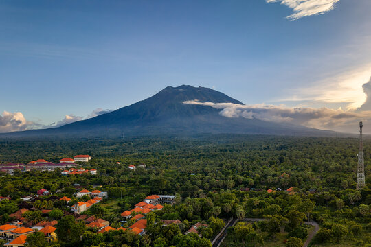 Mount Agung volcano towering over a lush tropical forest and village in Bali