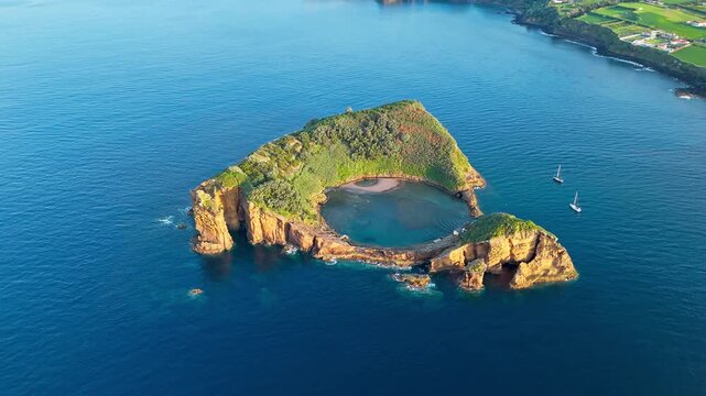 Circular volcanic islet with natural lagoon and steep cliffs, Sao Miguel, Azores, drone footage