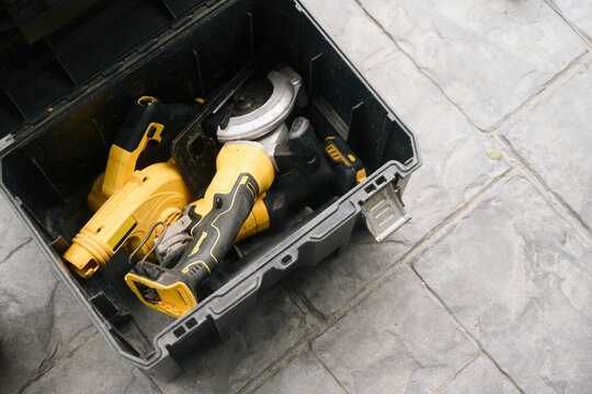 Yellow Power Tools in Open Black Plastic Toolbox on Stone Floor, Overhead View