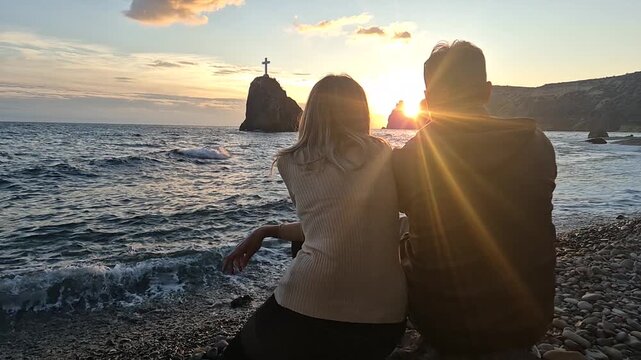 Couple sunset beach watching the glorious sun flare over the ocean and a towering sea stack Vertical video