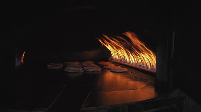 Thin Arabic bread shrak or pita, with lamb meat being cooked inside traditional oven, gas flames over metal plate