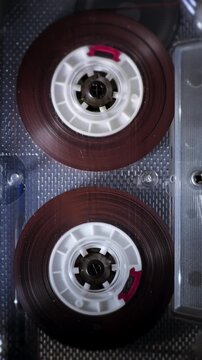 Vintage Audio Cassette Reels Spinning. Retro compact cassette tape with spinning reels on black background.	
