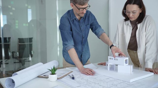 Architects and urban planners are working together, analyzing building plans and creating a small scale architectural model for a new residential or commercial project