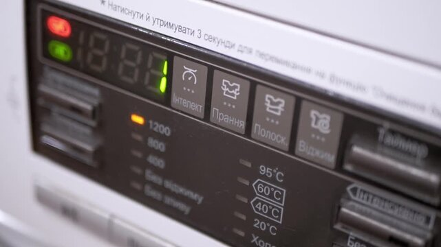 A close-up of a modern washing machine digital control panel with blinking lights indicating the selection of a spin cycle. Concept of household chores, domestic appliances, and modern home