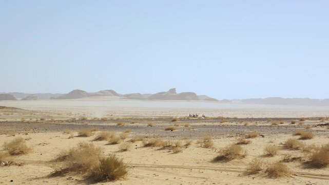 Four unrecognizable horse riders in Al Ula desert on a hot sunny day