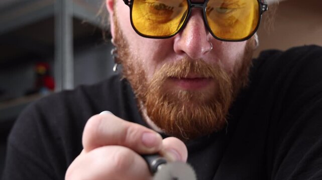 Concentrated artisan working with a cordless rotary hobby tool on a metal piece in a workshop