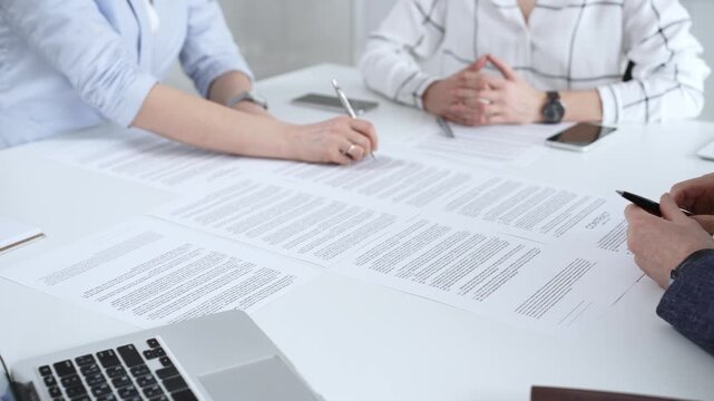 Business people discussing contract terms, outlining agreements, and reviewing legal documents during a corporate meeting, preparing for a significant partnership signing and negotiation